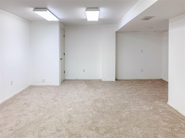 spare room featuring light carpet and baseboards