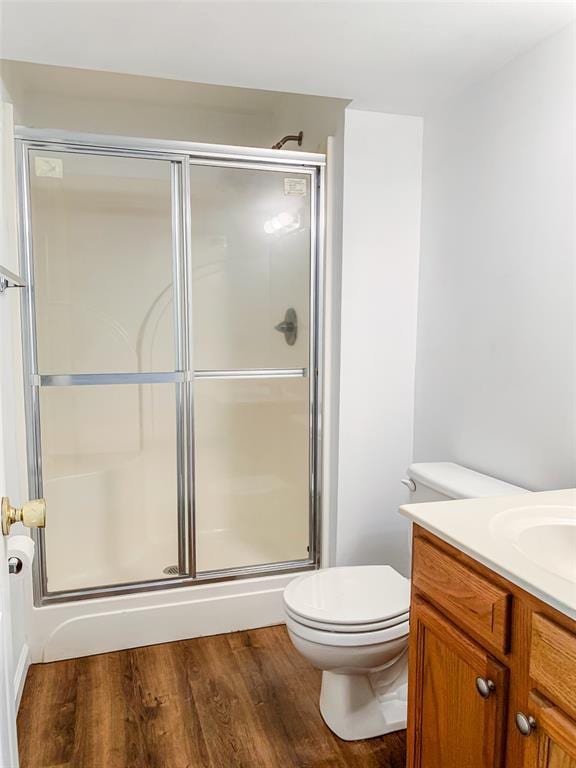 full bathroom with a shower stall, toilet, wood finished floors, and vanity