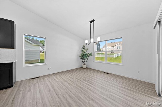 203 Homestretch Ln, Wentzville, MO 63385 - unfurnished dining area featuring light wood-style floors, plenty of natural light, a fireplace, a chandelier, and vaulted ceiling