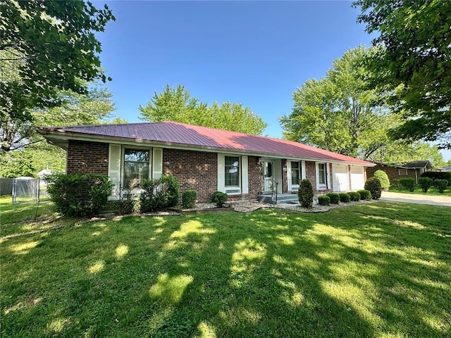 ranch-style home with brick siding, an attached garage, metal roof, and driveway