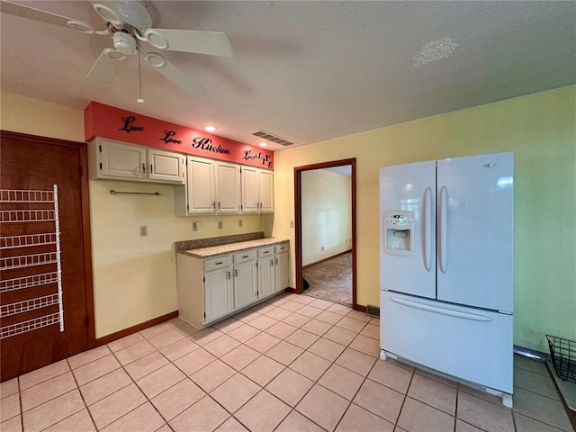 kitchen featuring white fridge with ice dispenser, light countertops, a ceiling fan, light tile patterned floors, and baseboards