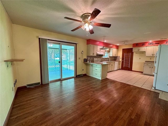 kitchen featuring white appliances, wood finished floors, a ceiling fan, under cabinet range hood, and baseboards
