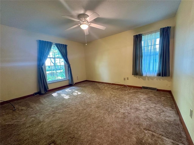 carpeted spare room featuring a ceiling fan and baseboards