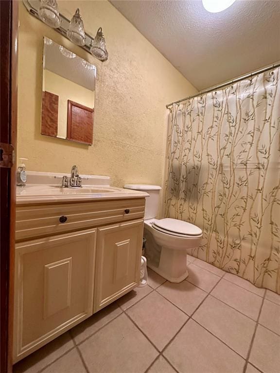 bathroom featuring a textured wall, a textured ceiling, tile patterned flooring, vanity, and toilet