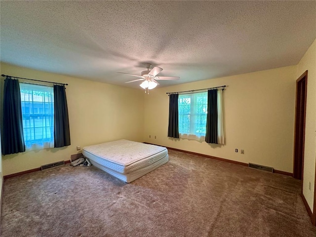 carpeted bedroom with a textured ceiling, ceiling fan, and baseboards