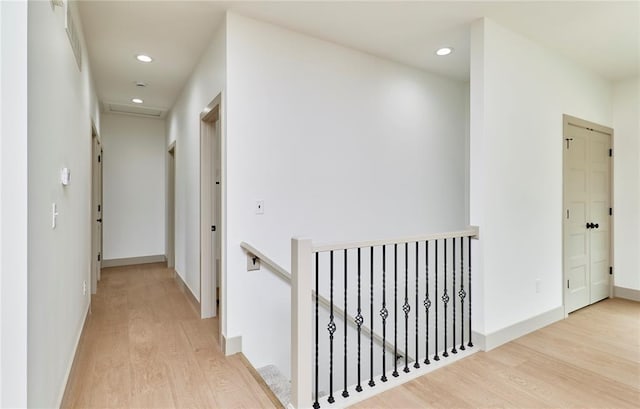 hallway featuring light wood-type flooring, an upstairs landing, recessed lighting, and baseboards