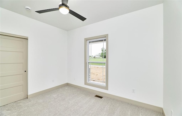 spare room featuring light carpet, a ceiling fan, a smoke detector, and baseboards