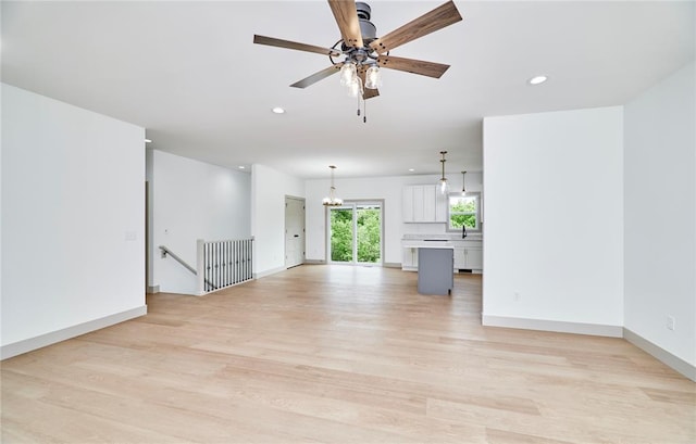 unfurnished living room featuring light wood finished floors, recessed lighting, a chandelier, ceiling fan, and baseboards