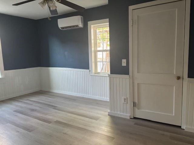 423 W Mckinley Ave, Bernie, MO 63822 - spare room with an AC wall unit, a ceiling fan, wood finished floors, and a wainscoted wall
