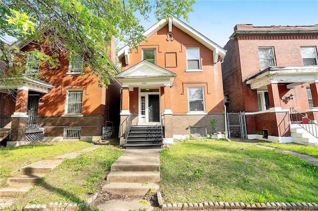 view of front of house featuring a front lawn, brick siding, and a gate