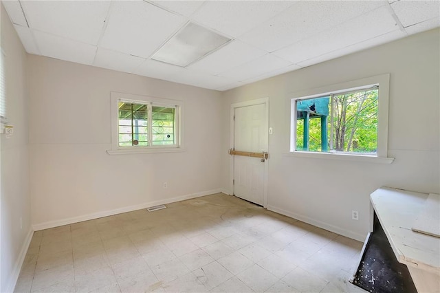 unfurnished room featuring healthy amount of natural light, a paneled ceiling, and baseboards