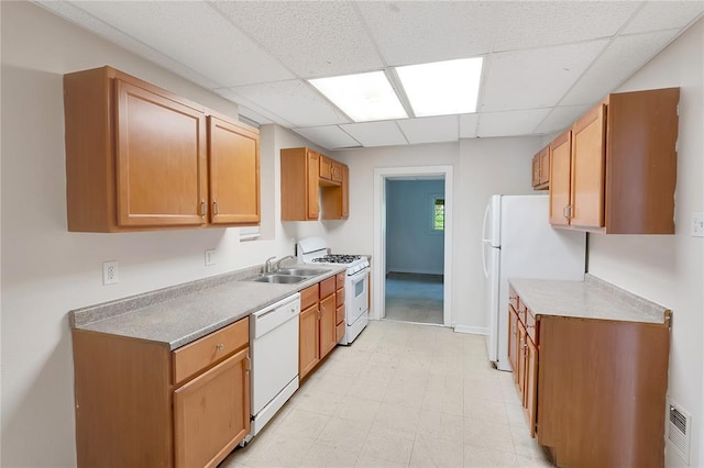 kitchen with white appliances, a sink, a paneled ceiling, light flooring, and baseboards