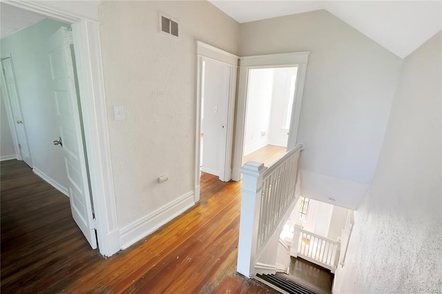 hallway featuring an upstairs landing, wood finished floors, vaulted ceiling, and baseboards