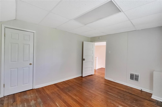 spare room with wood-type flooring, a paneled ceiling, and baseboards