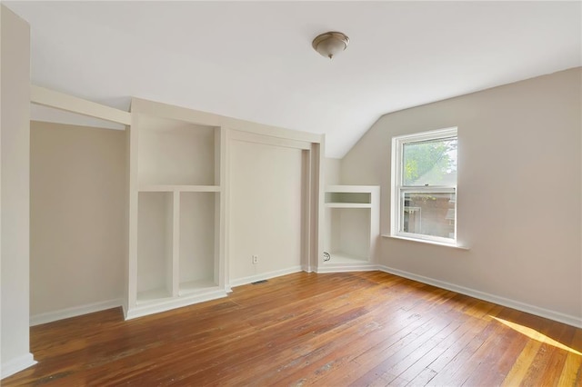 unfurnished bedroom featuring vaulted ceiling, wood-type flooring, baseboards, and a closet