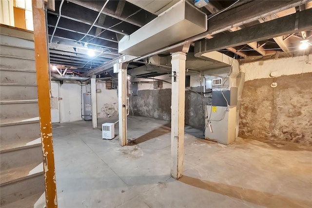 unfinished below grade area featuring water heater, stairway, and heating unit