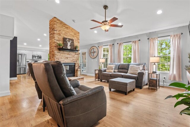 living room with vaulted ceiling, a fireplace, ceiling fan, recessed lighting, and light wood-style flooring