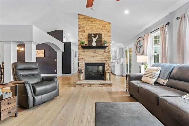 living room with decorative columns, a ceiling fan, vaulted ceiling, wood finished floors, and a fireplace