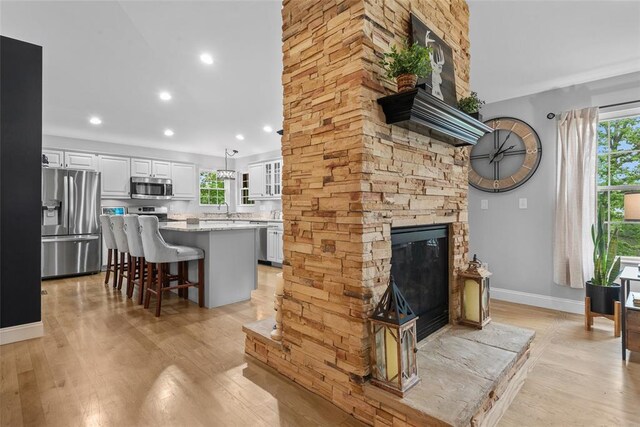 living room featuring healthy amount of natural light, light wood finished floors, baseboards, and recessed lighting