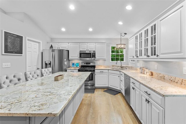 kitchen with appliances with stainless steel finishes, light wood-style floors, a sink, white cabinetry, and recessed lighting