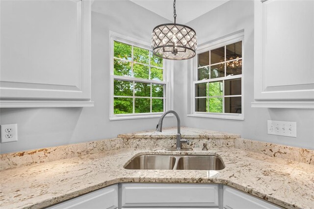 kitchen featuring a sink, a chandelier, white cabinetry, and plenty of natural light