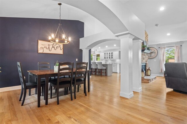 dining space with ornate columns, light wood-style floors, recessed lighting, baseboards, and a fireplace