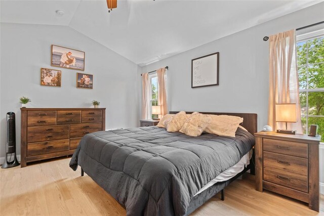 bedroom featuring light wood-style floors, vaulted ceiling, and a ceiling fan