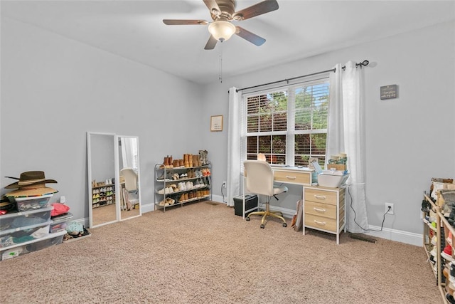 carpeted office space with a ceiling fan and baseboards