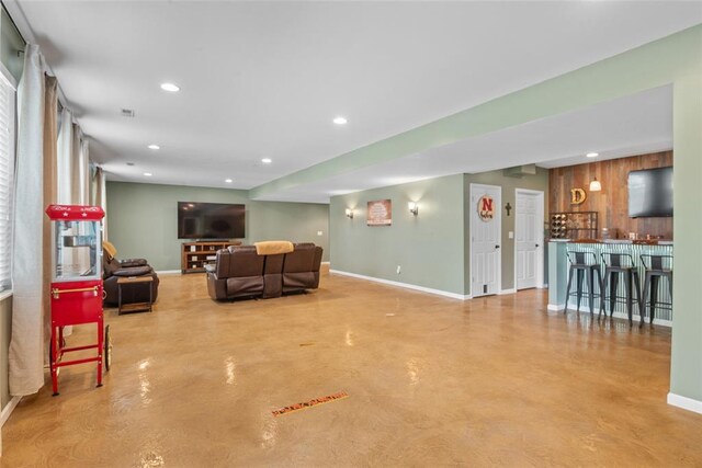 living room with concrete flooring, baseboards, bar, and recessed lighting