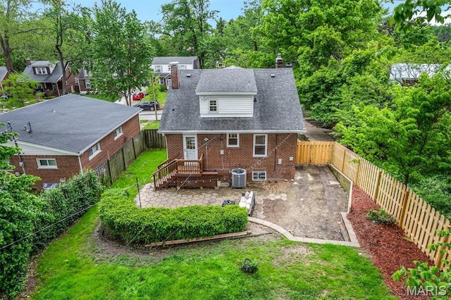 7439 Wellington Ave, University City, MO 63130 - back of house featuring brick siding, a fenced backyard, view of wooded area, a patio area, and a chimney