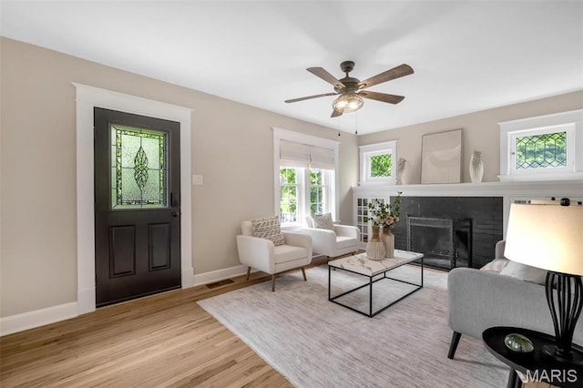 7439 Wellington Ave, University City, MO 63130 - living area with wood finished floors, a brick fireplace, and a ceiling fan