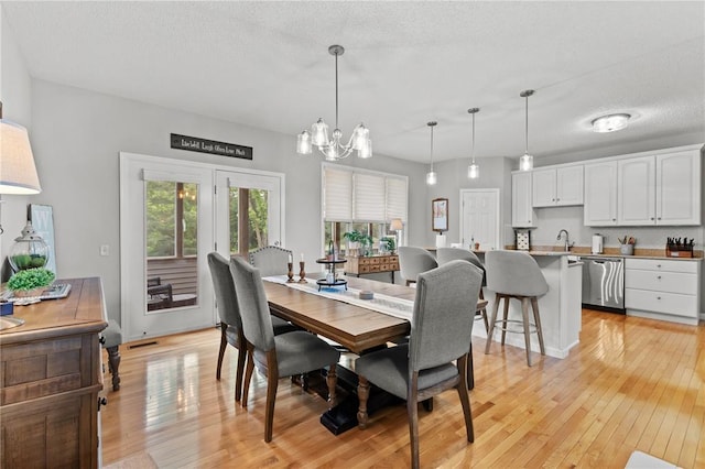 2056 Hawks Landing Dr, Lake St Louis, MO 63367 - dining space with light wood-style floors, a chandelier, and a textured ceiling