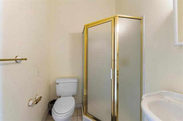 3534 Washington Ave, Saint Louis, MO 63103 - bathroom featuring a shower stall, toilet, tile patterned flooring, and a sink