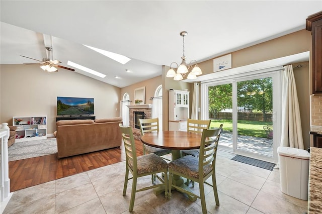 14 Heavenly Valley Dr, Dardenne Prairie, MO 63368 - dining area with light tile patterned flooring, a brick fireplace, a skylight, vaulted ceiling, and ceiling fan