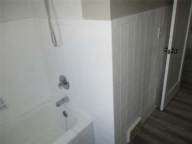full bath with washtub / shower combination and wood finished floors