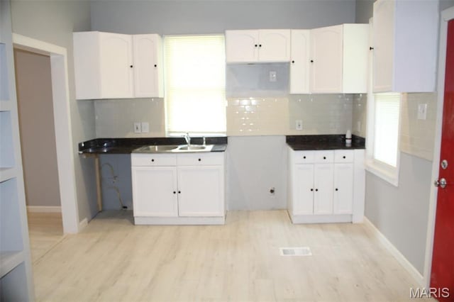 5379 Wabada Ave, Saint Louis, MO 63112 - kitchen featuring white cabinets, light wood-style flooring, and backsplash