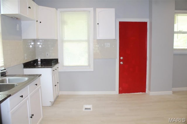 5379 Wabada Ave, Saint Louis, MO 63112 - kitchen featuring white cabinetry, decorative backsplash, and light wood-style flooring
