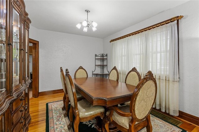 6266 Marmaduke Ave, Saint Louis, MO 63139 - dining room with a chandelier, light wood-style flooring, baseboards, and a textured wall