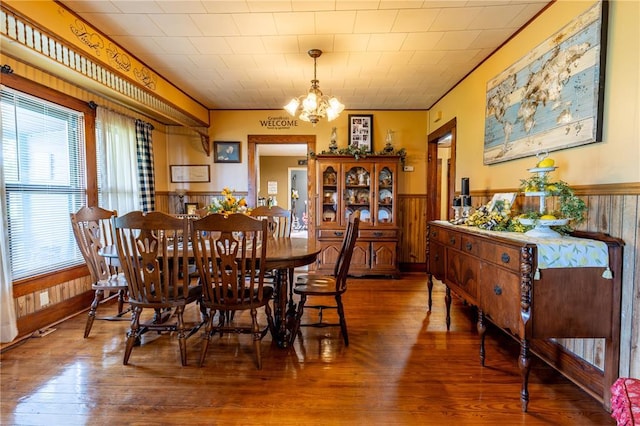 506 N Garfield, East Prairie, MO 63845 - dining space featuring wood-type flooring, a chandelier, wainscoting, wooden walls, and ornamental molding