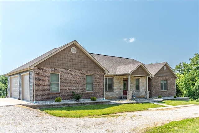 view of front of property with driveway, an attached garage, stone siding, a front lawn, and brick siding