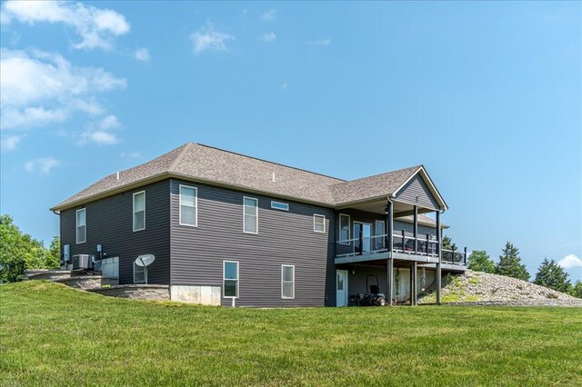 rear view of property with central AC and a yard