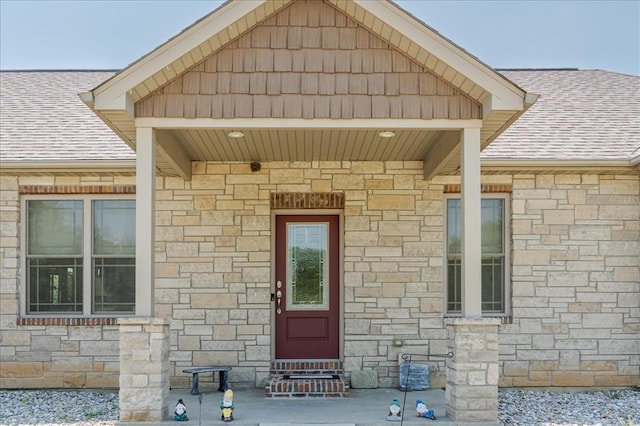 property entrance featuring a shingled roof and stone siding