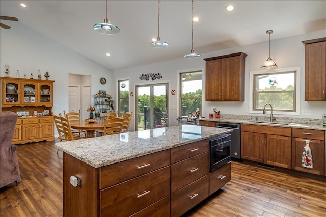 kitchen with a sink, dark wood-type flooring, a center island, light stone countertops, and dishwashing machine