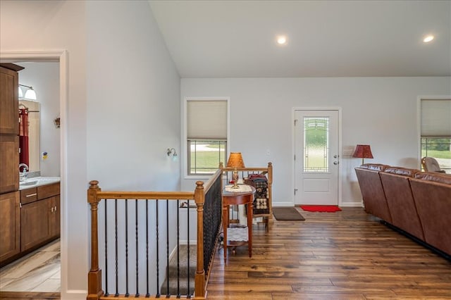hallway featuring an upstairs landing, hardwood / wood-style flooring, lofted ceiling, recessed lighting, and a sink