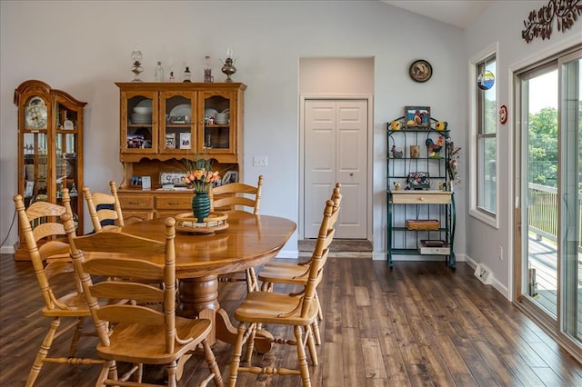 dining room featuring lofted ceiling, dark wood-type flooring, and baseboards
