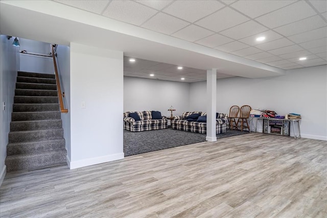 finished basement featuring baseboards, wood finished floors, stairway, recessed lighting, and a drop ceiling