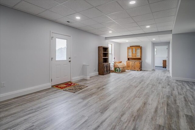 unfurnished living room with light wood finished floors, baseboards, a paneled ceiling, and recessed lighting