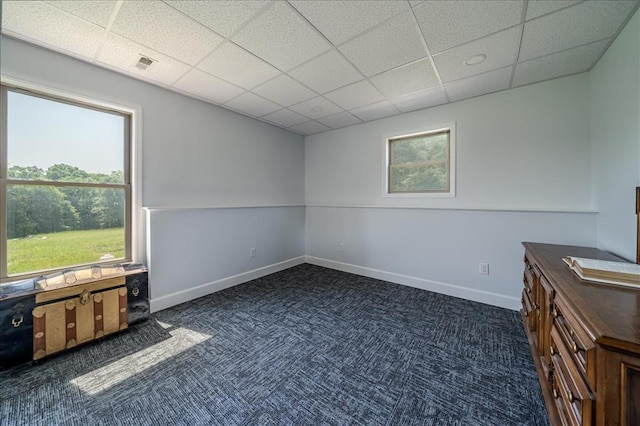 unfurnished bedroom featuring a drop ceiling, carpet floors, and baseboards