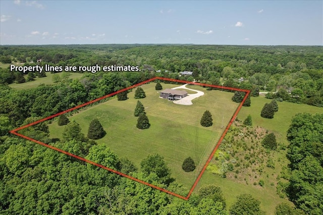 aerial view of property and surrounding area featuring a heavily wooded area and property parcel outlined