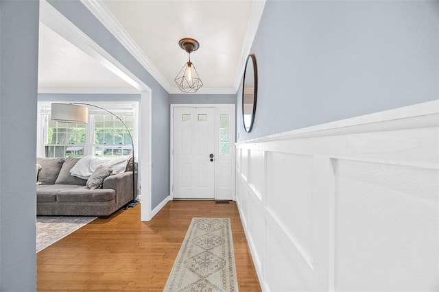 foyer entrance with crown molding and wood finished floors